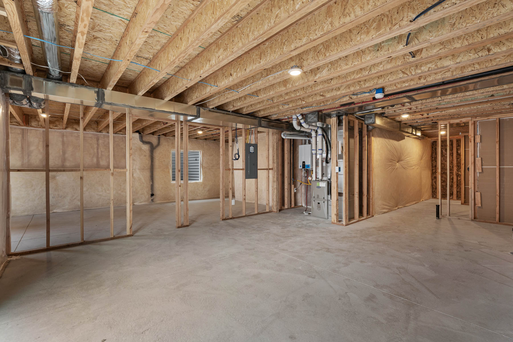 Unfinished basement featuring extensive wood framing, concrete flooring, exposed ceiling joists, and recessed lighting