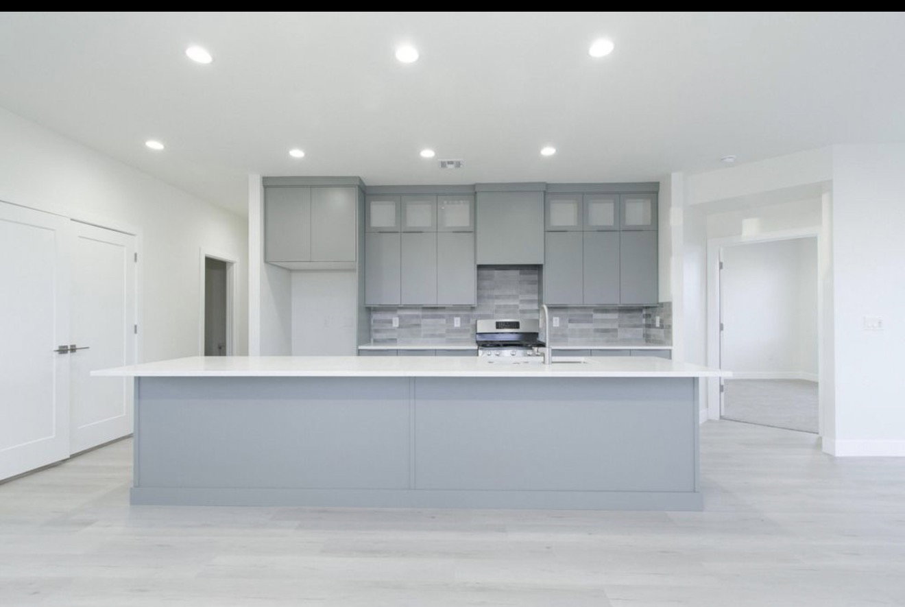 Kitchen with gray cabinetry, a large island, recessed lighting, light wood finished floors, and decorative backsplash