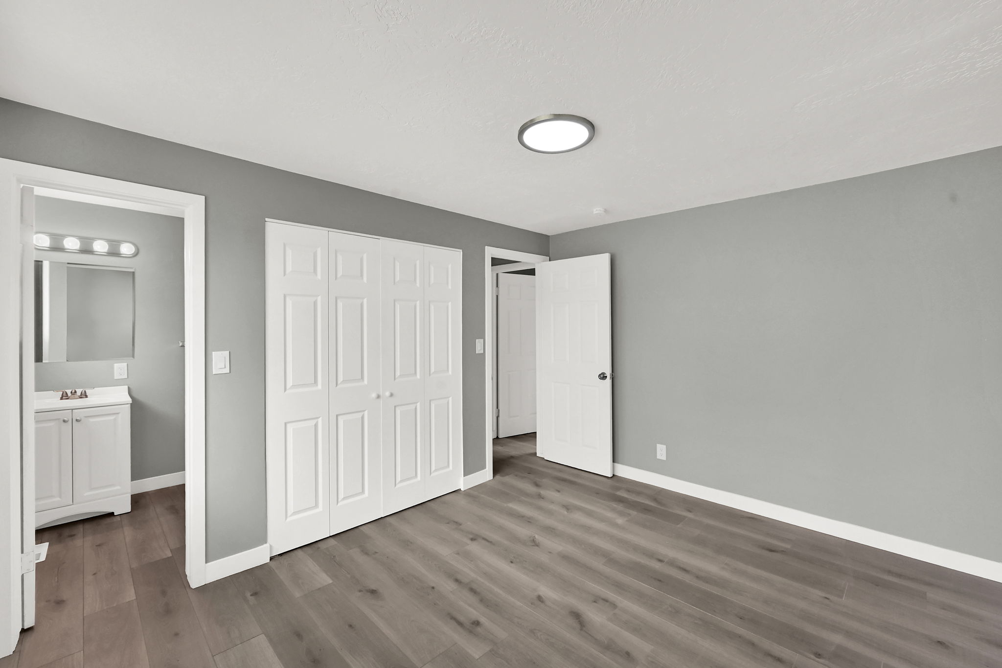 Primary bedroom featuring light gray walls, wood-finish flooring, and white baseboards