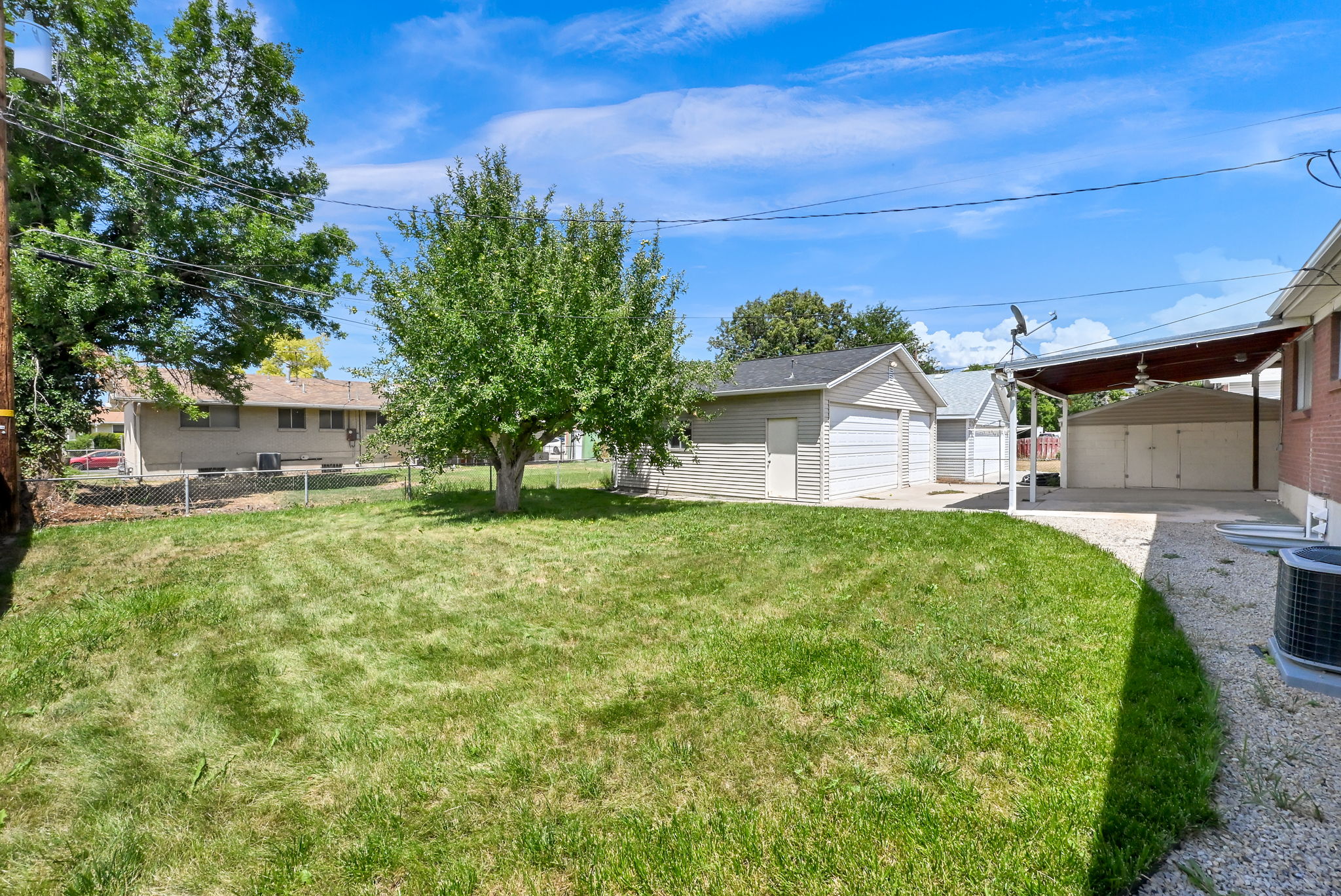 Expansive grassy yard area with a mature tree.