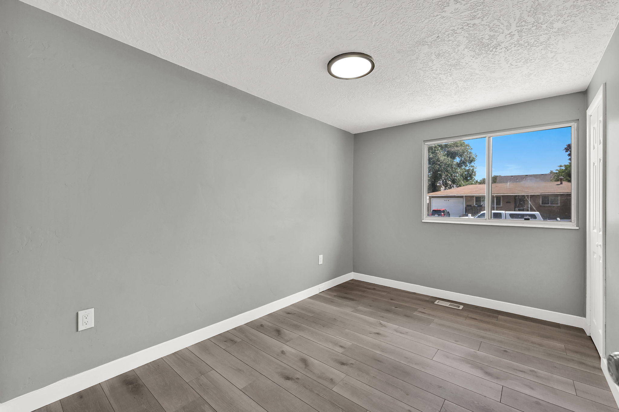Interior room featuring wood-finish flooring, light gray walls, and white baseboards