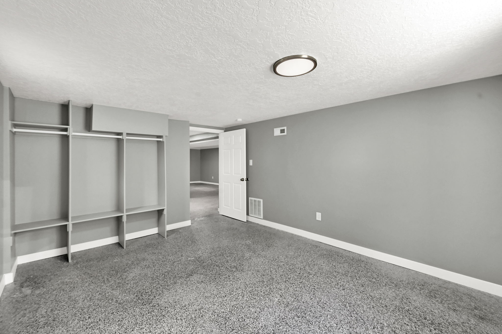 Bedroom with built-in closet shelving, a classic white door, and neutral gray walls.