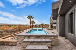 View of pool with patio surround, an in-ground hot tub, a mountain view, and a balcony