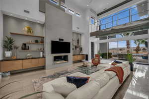 Living area with a high ceiling, recessed lighting, and a glass covered fireplace