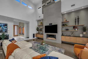 Living room with built in shelves, recessed lighting, a large fireplace, and a high ceiling
