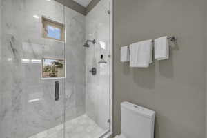 Bathroom featuring toilet and a marble finish shower