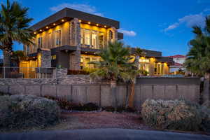 Contemporary house featuring stone siding, stucco siding, a balcony, and a fenced front yard