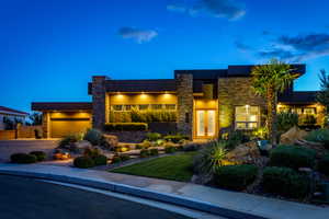 Modern home featuring stone siding, driveway, stucco siding, and a front lawn