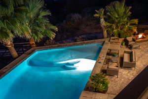 Pool at twilight featuring a patio area, an outdoor pool, and a fire pit