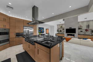 Kitchen featuring open floor plan, island range hood, stainless steel appliances, a kitchen island with sink, and recessed lighting