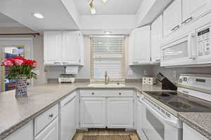 Kitchen with white appliances, white cabinetry, recessed lighting, and light wood-style floors new faucett