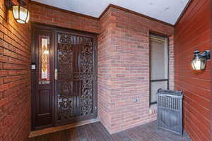 View of exterior entry with brick siding covered porch