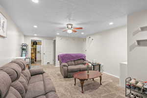 Living room with light carpet, ceiling fan, a textured ceiling, and recessed lighting