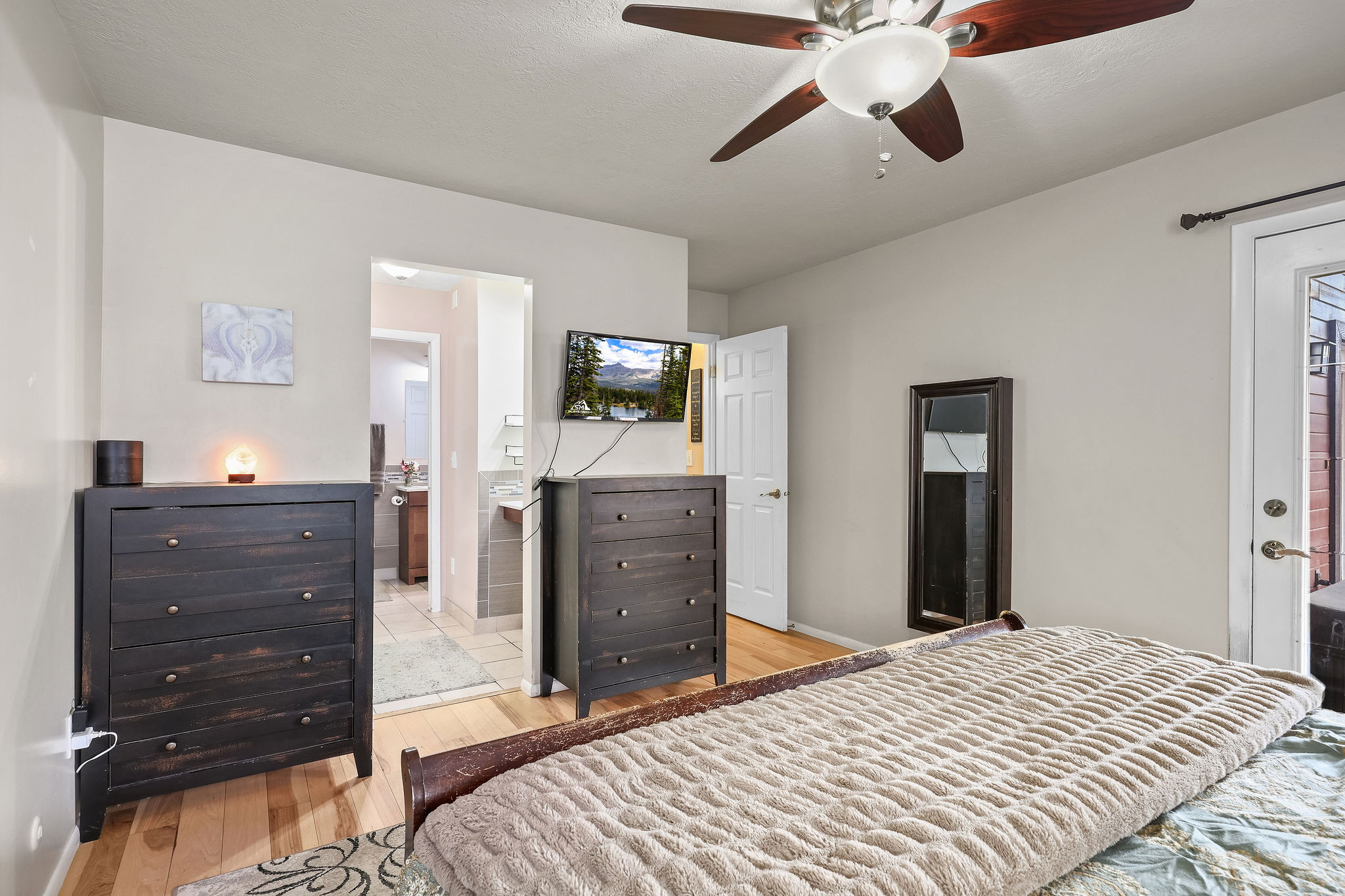 Bedroom featuring light wood finished floors, ceiling fan, and ensuite bathroom