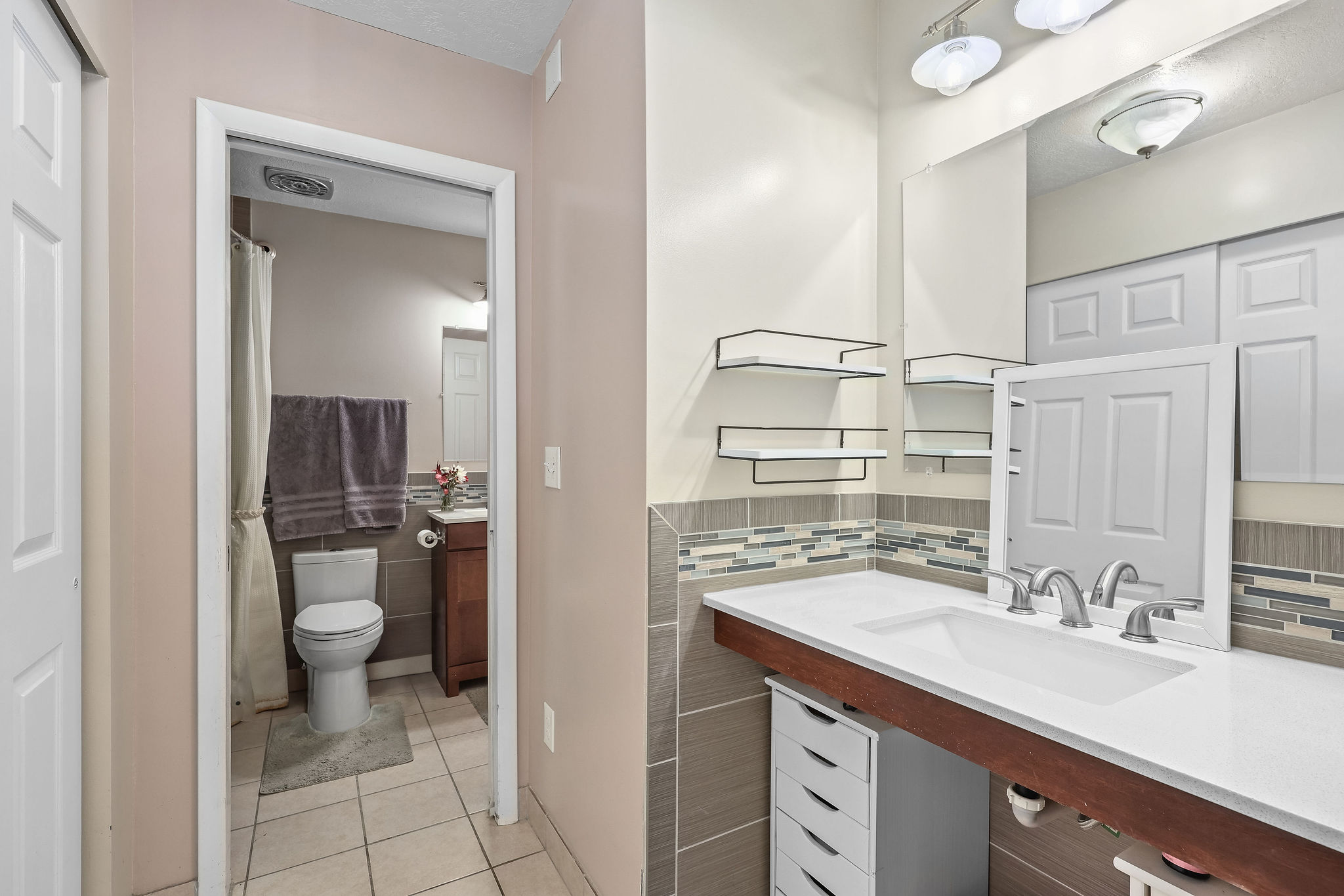 Bathroom with vanity, a shower with shower curtain, light tile patterned floors, and decorative backsplash