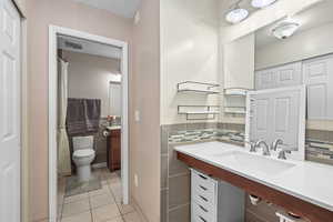 Bathroom with vanity, a shower with shower curtain, light tile patterned floors, and decorative backsplash