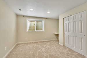 Unfurnished bedroom with light carpet and a closet