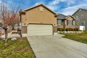 View of front of house featuring brick siding, stucco siding, concrete driveway, and a garage