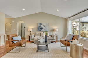 Living room featuring arched walkways, light wood-type flooring, and recessed lighting