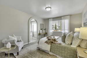 Carpeted bedroom featuring arched walkways and baseboards