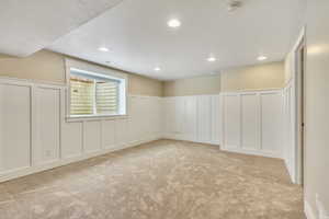 Basement with a decorative wall, a wainscoted wall, light carpet, and recessed lighting
