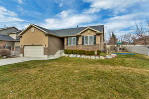 View of front facade featuring stucco siding, brick siding, concrete driveway, an attached garage, and a playground