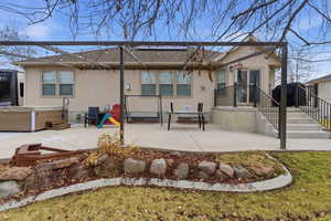 Rear view of property with a patio, roof with shingles, a hot tub, stucco siding, and solar panels