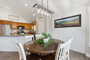 Dining area with vaulted ceiling, light wood-style floors, wood walls, and recessed lighting