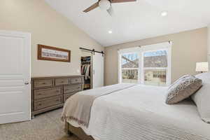 Bedroom featuring a walk in closet, light colored carpet, a barn door, recessed lighting, and ceiling fan