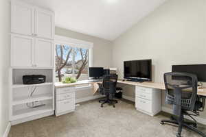 Office area featuring vaulted ceiling and light carpet