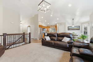 Living room featuring hanging lights, vaulted ceiling, light colored carpet, and arched walkways