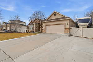 View of front of home with a gate, stucco siding, driveway, stone siding, and an attached garage
