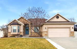 View of front of property with stone siding, stucco siding, an attached garage, and driveway