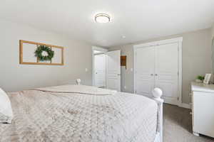 Bedroom with light colored carpet and a closet
