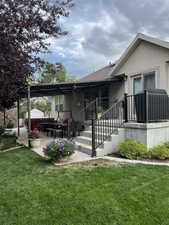 Rear view of house featuring a patio area, stucco siding, and a lawn