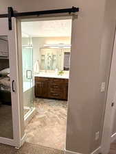 Ensuite bathroom featuring vanity, brick patterned floors, a stall shower, and a textured ceiling