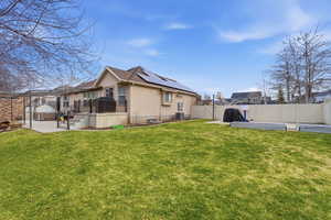 Rear view of property featuring a patio area, a fenced backyard, roof mounted solar panels, and a gate