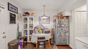 Kitchen featuring freestanding refrigerator, decorative light fixtures, dark wood finished floors, white cabinetry, and light countertops