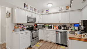 Kitchen with white cabinetry, light countertops, and stainless steel appliances