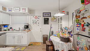 Kitchen with stainless steel appliances, white cabinetry, light countertops, backsplash, and light wood-style floors