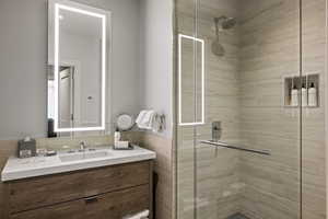 Bathroom with vanity, a shower stall, tile walls, and wainscoting