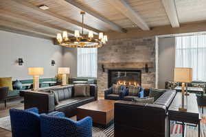 Living room featuring wood finished floors, a fireplace, a chandelier, and beamed ceiling