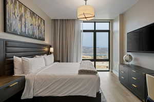 Bedroom with floor to ceiling windows and light wood finished floors