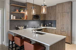 Kitchen with modern cabinets, light wood-type flooring, open shelves, and a breakfast bar area