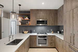 Kitchen featuring stainless steel appliances, hanging light fixtures, open shelves, modern cabinets, and backsplash