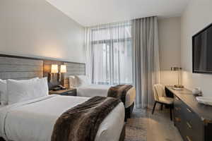 Bedroom with wood finished floors and an office area