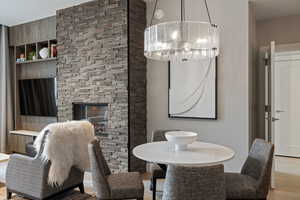 Dining room with wood finished floors, a stone fireplace, and suspended lighting