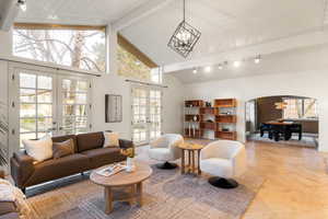 Living area featuring french doors, arched walkways, hanging lights, and light tile patterned floors