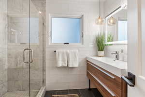 Full bathroom featuring vanity, a shower stall, and tile walls