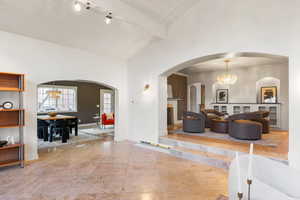 Living area featuring hanging lights, a high wooden beamed ceiling, and arched walkways